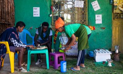 women serving food to two men outside